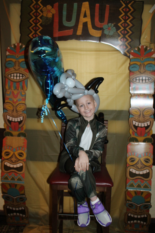 Elias sitting with Shark and Dolphin Balloons